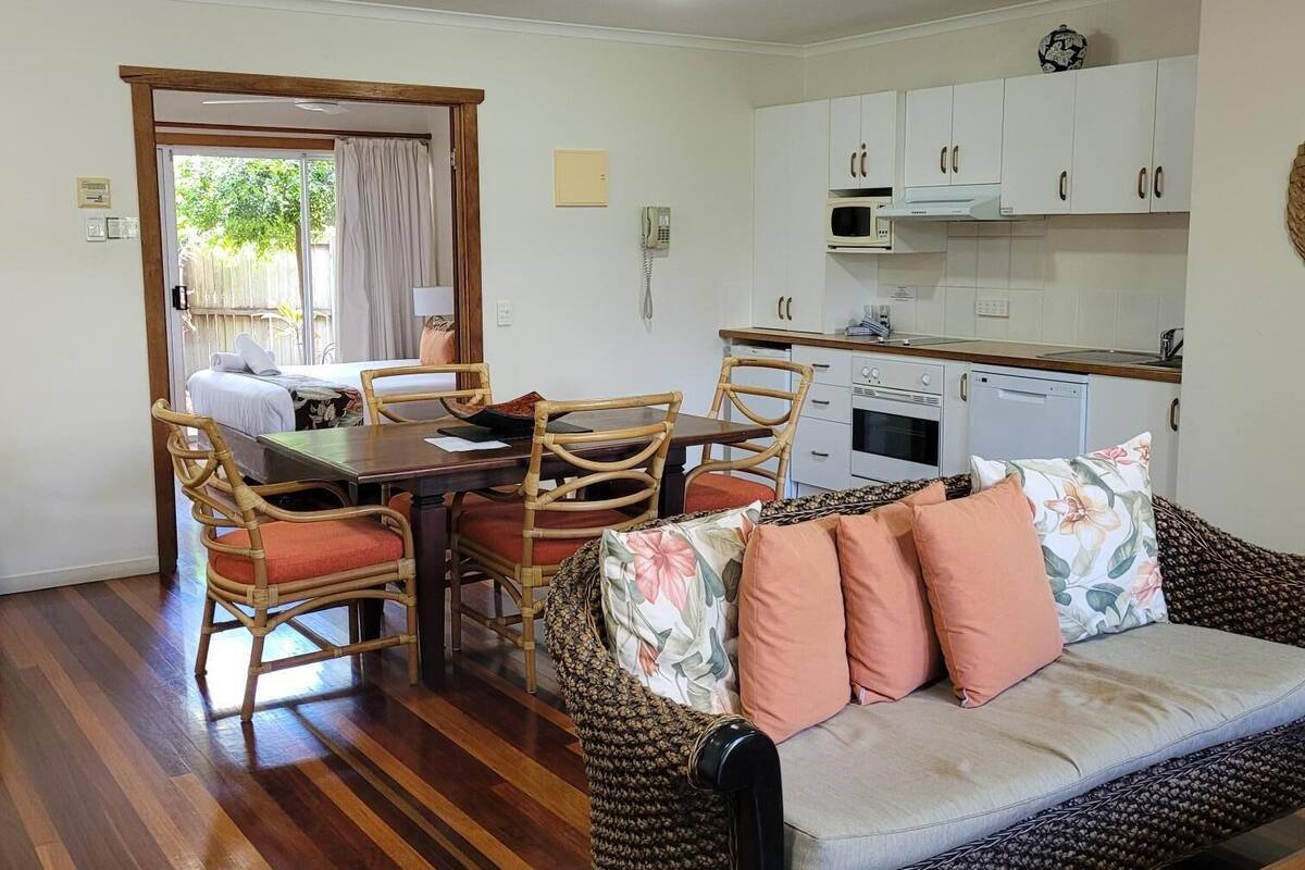 Un espacio habitable compacto con comedor, kitchenette y un sofá con cojines estampados.