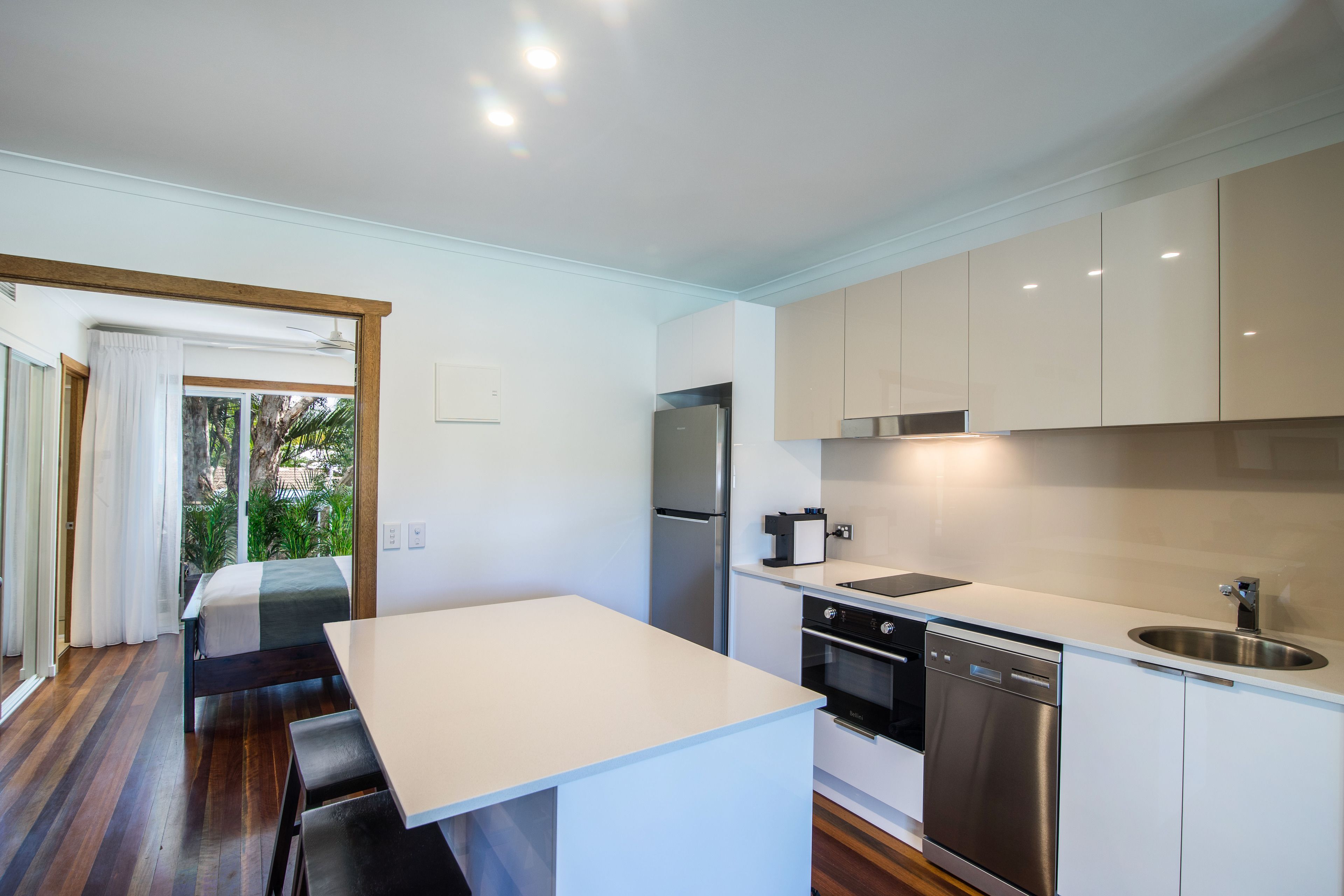 A modern kitchen with white cabinetry, stainless steel appliances, and a wooden dining table.
