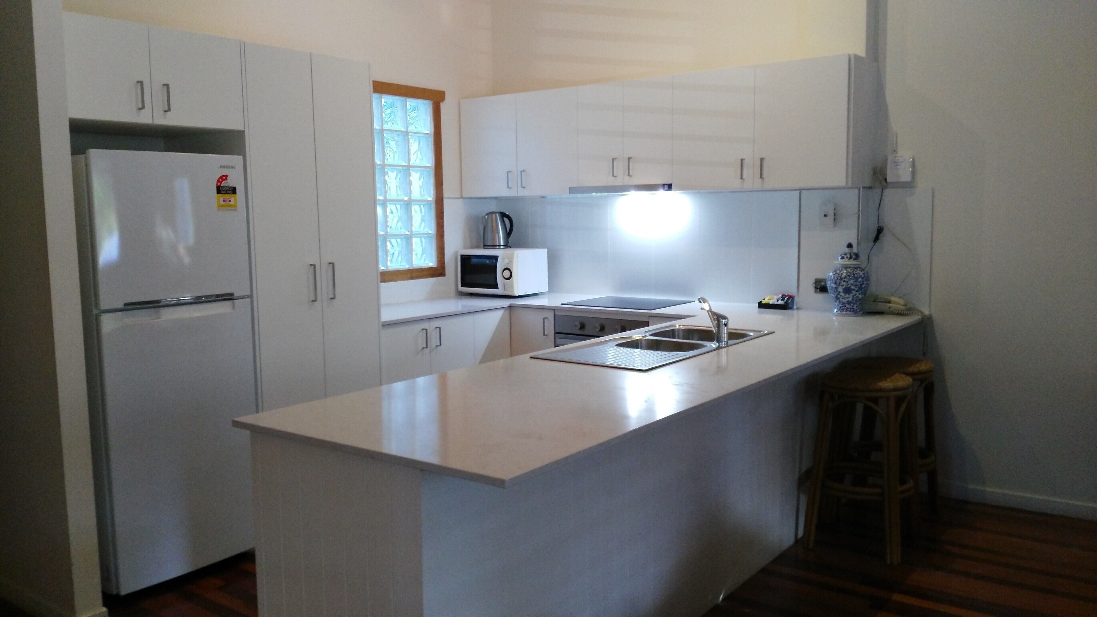 A modern kitchen with white cabinets, a built-in microwave, and a stainless steel sink.