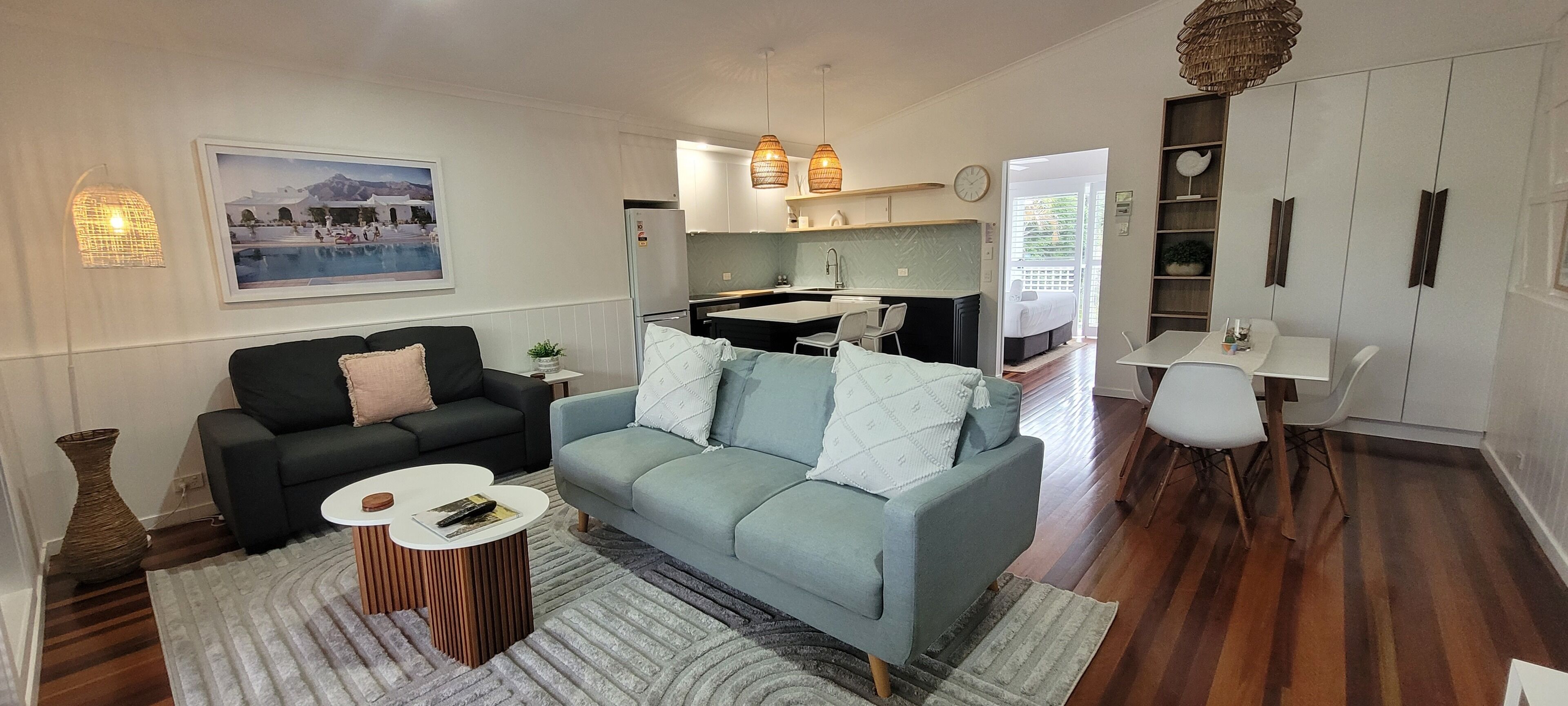 A modern living room with a sofa, coffee table, and a dining area with a table and chairs.