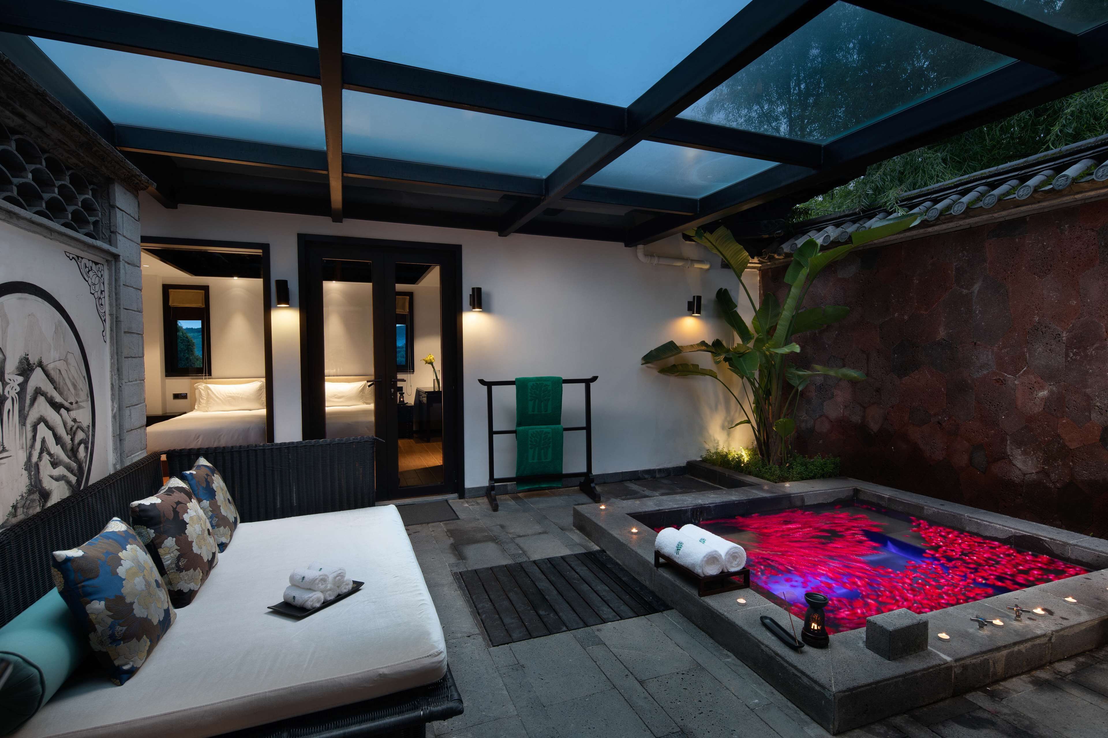 A spa area with a hot tub, a massage table, and a wall with a traditional design.