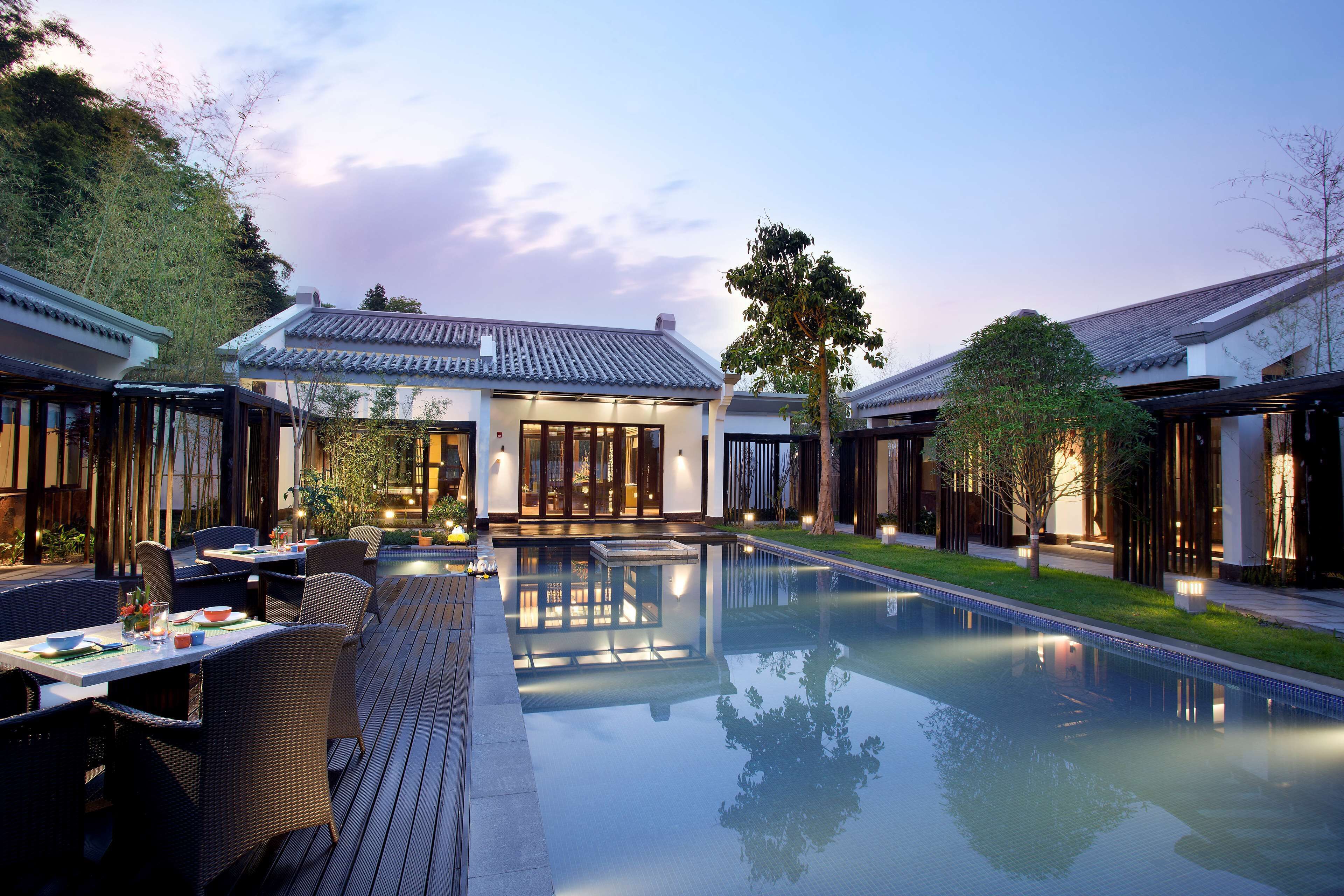 A modern outdoor pool area with seating and a building in the background.