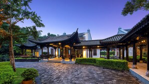 A traditional pavilion-style building with tiled roofs and wooden beams, surrounded by well-maintained gardens and a cobblestone pathway. - Banyan Tree Tengchong (Baoshan)