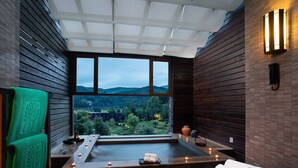 A modern spa room with a large window offering a view of a forested landscape. - Banyan Tree Tengchong (Baoshan)