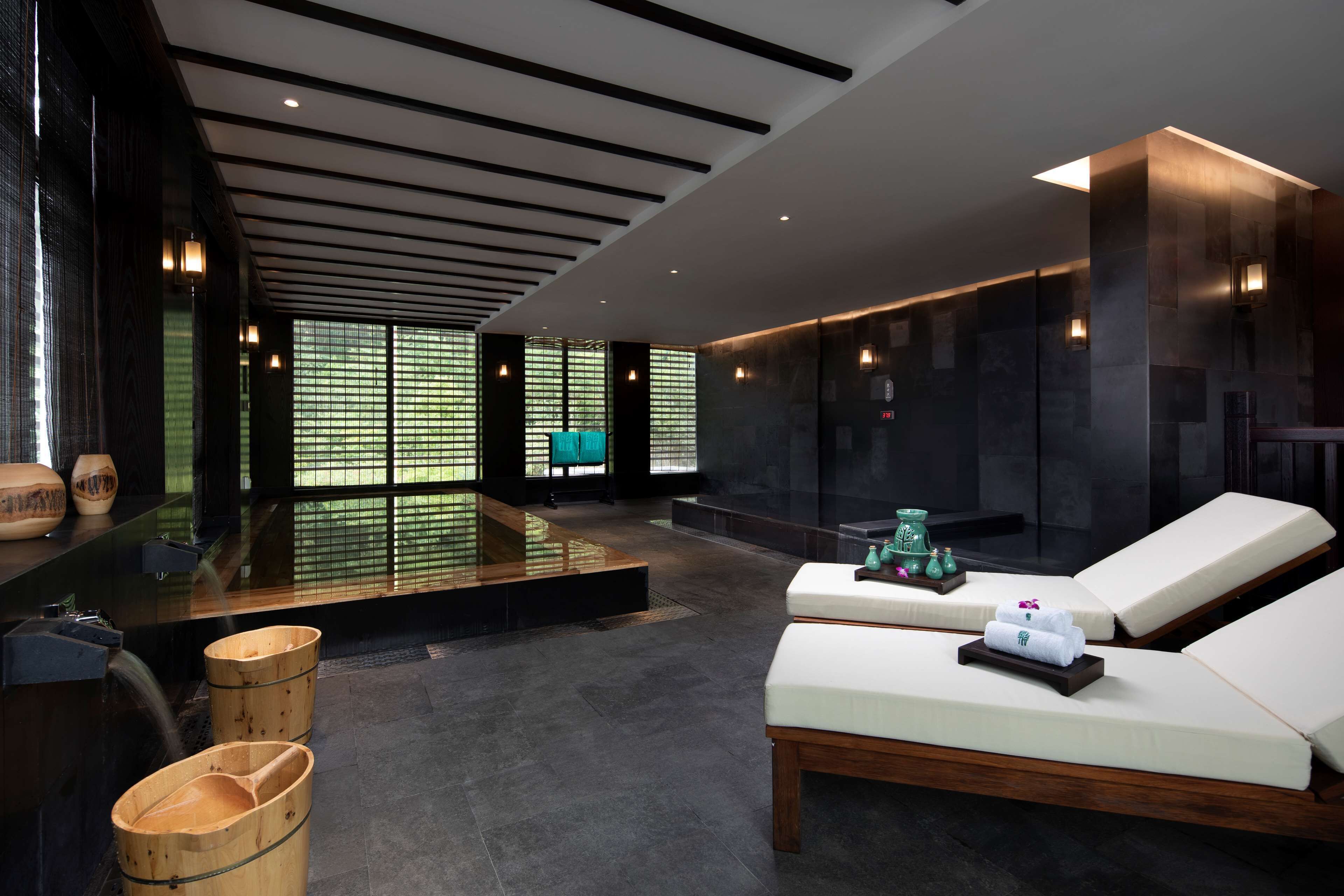 A modern spa area with a relaxation zone, wooden buckets, and a water feature.