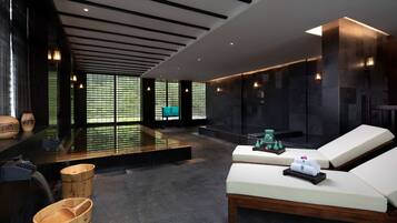 A modern spa area with a relaxation zone, wooden buckets, and a water feature.