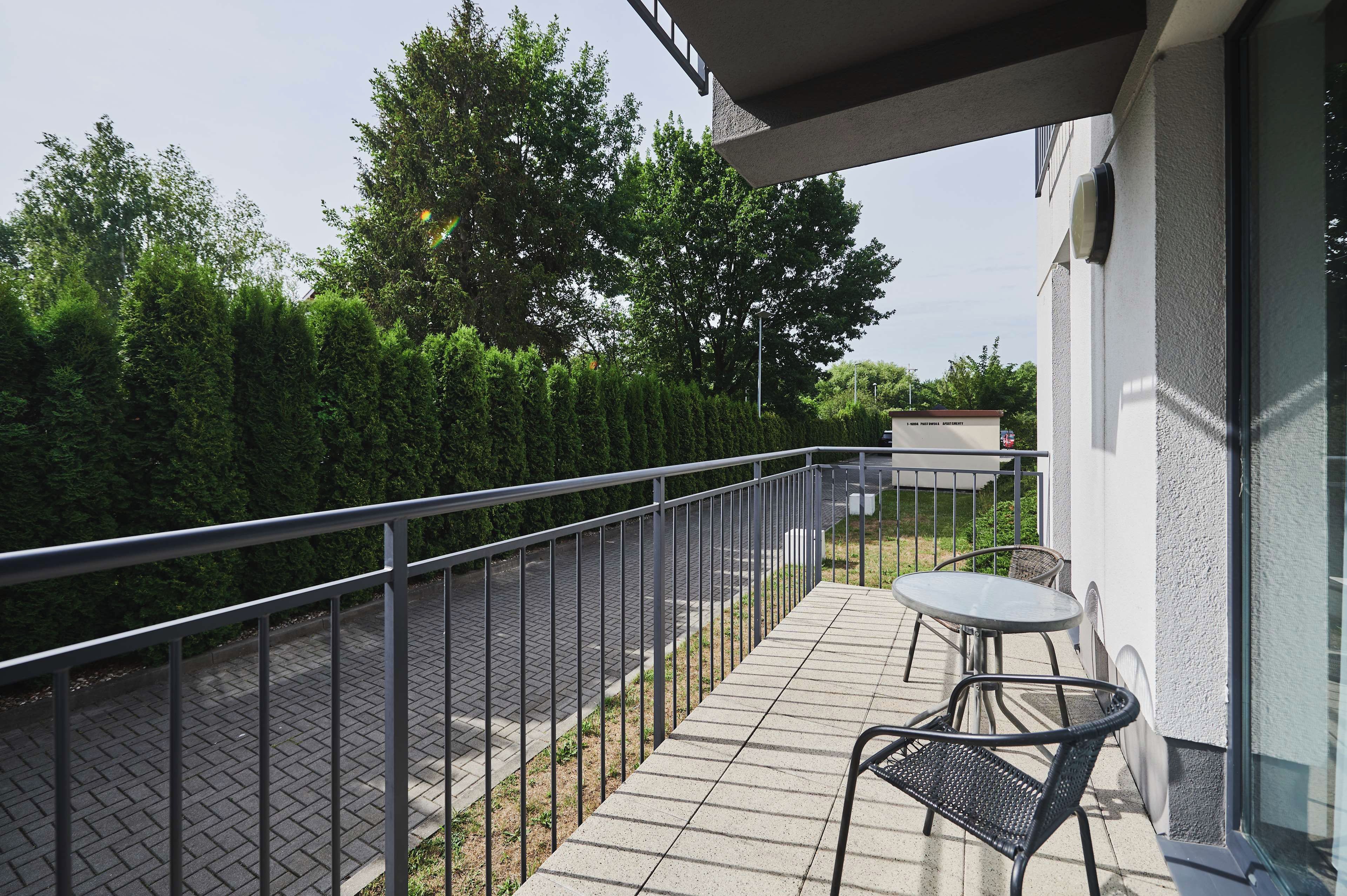 A balcony with a metal railing, a table, and two chairs.