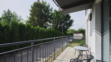 A balcony with a metal railing, a table, and two chairs.