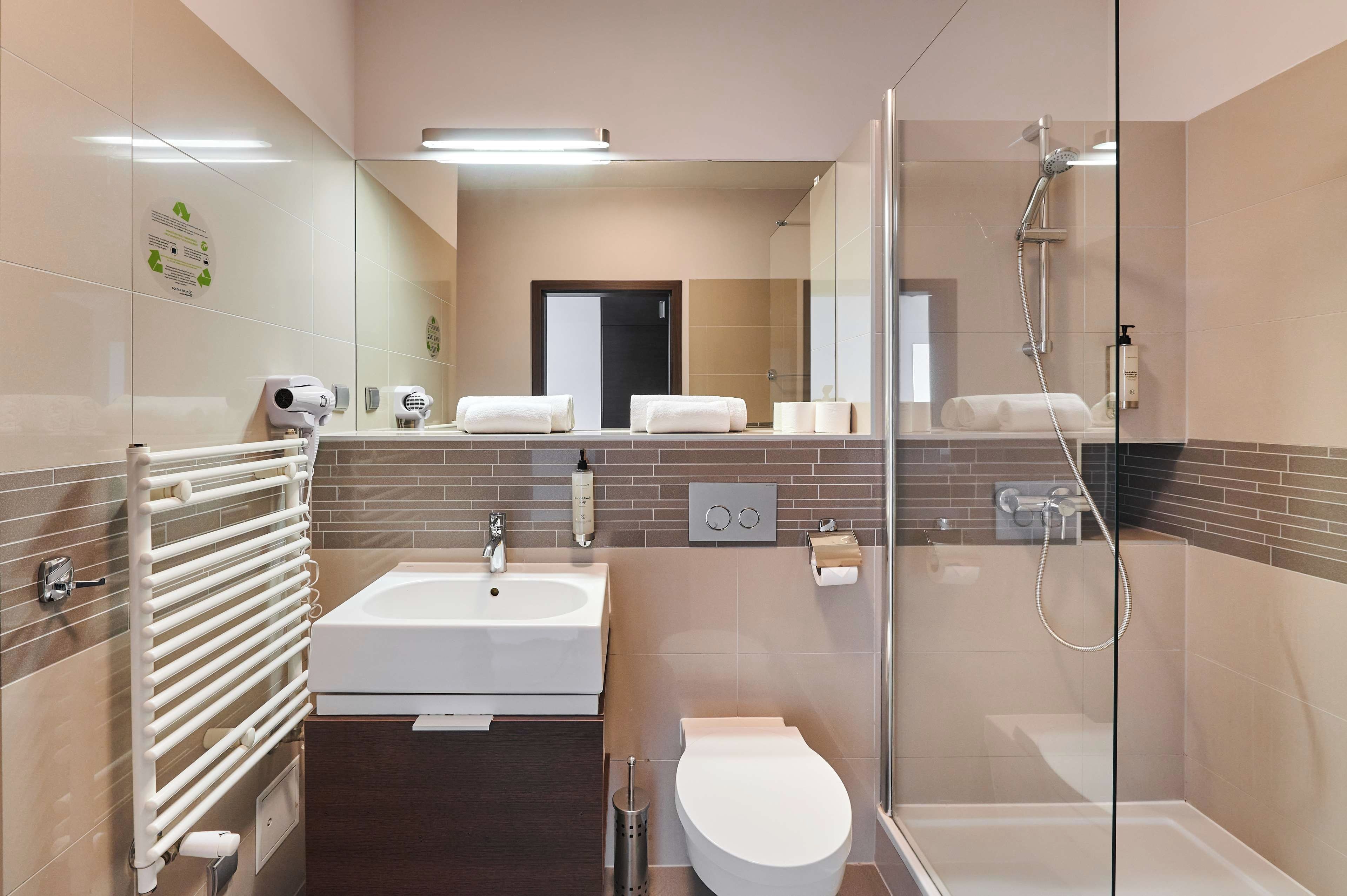 A modern bathroom with a glass shower enclosure, a white sink, and a toilet.
