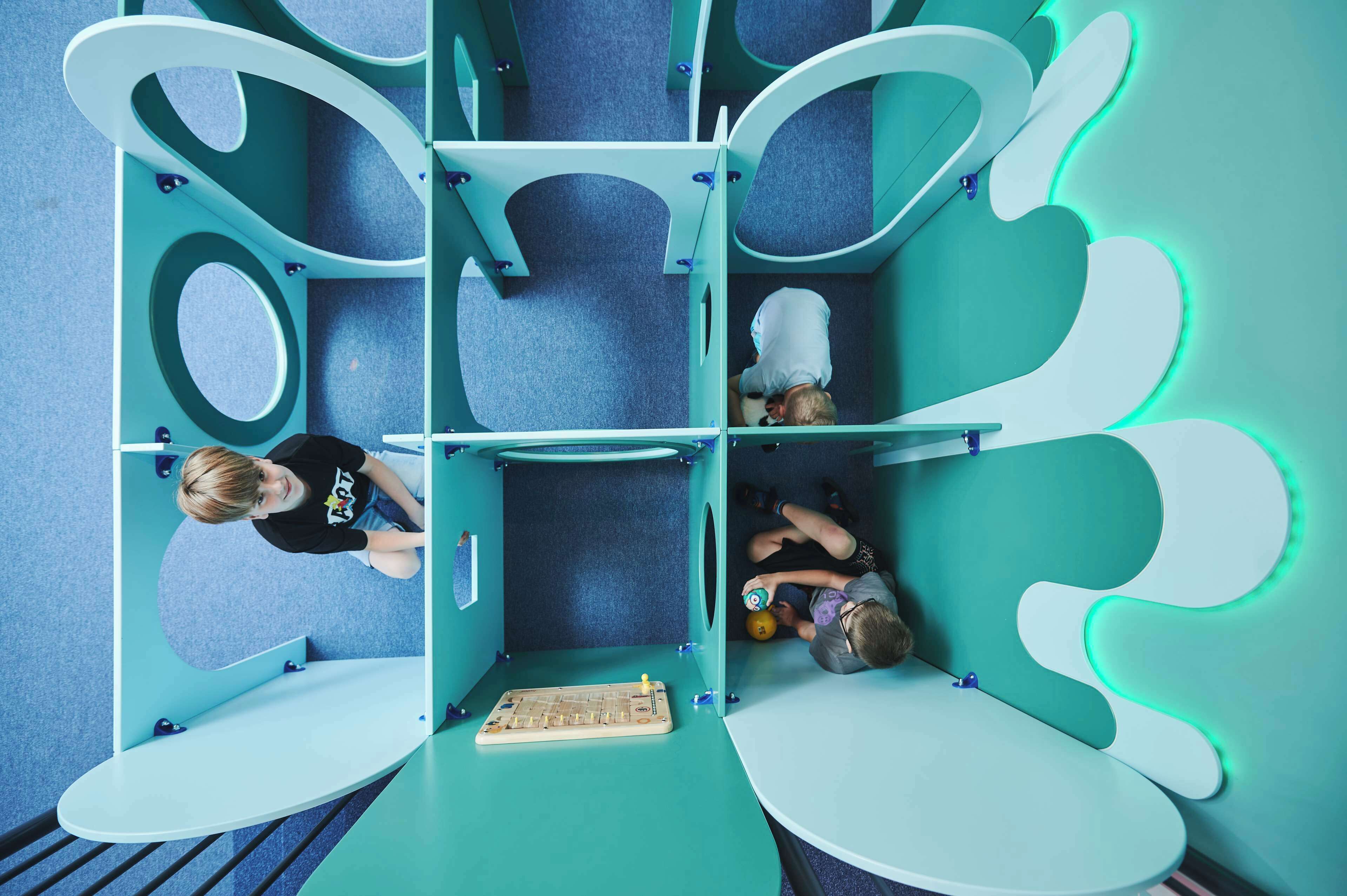 A room with a unique geometric design, featuring multiple seating areas and a central table.