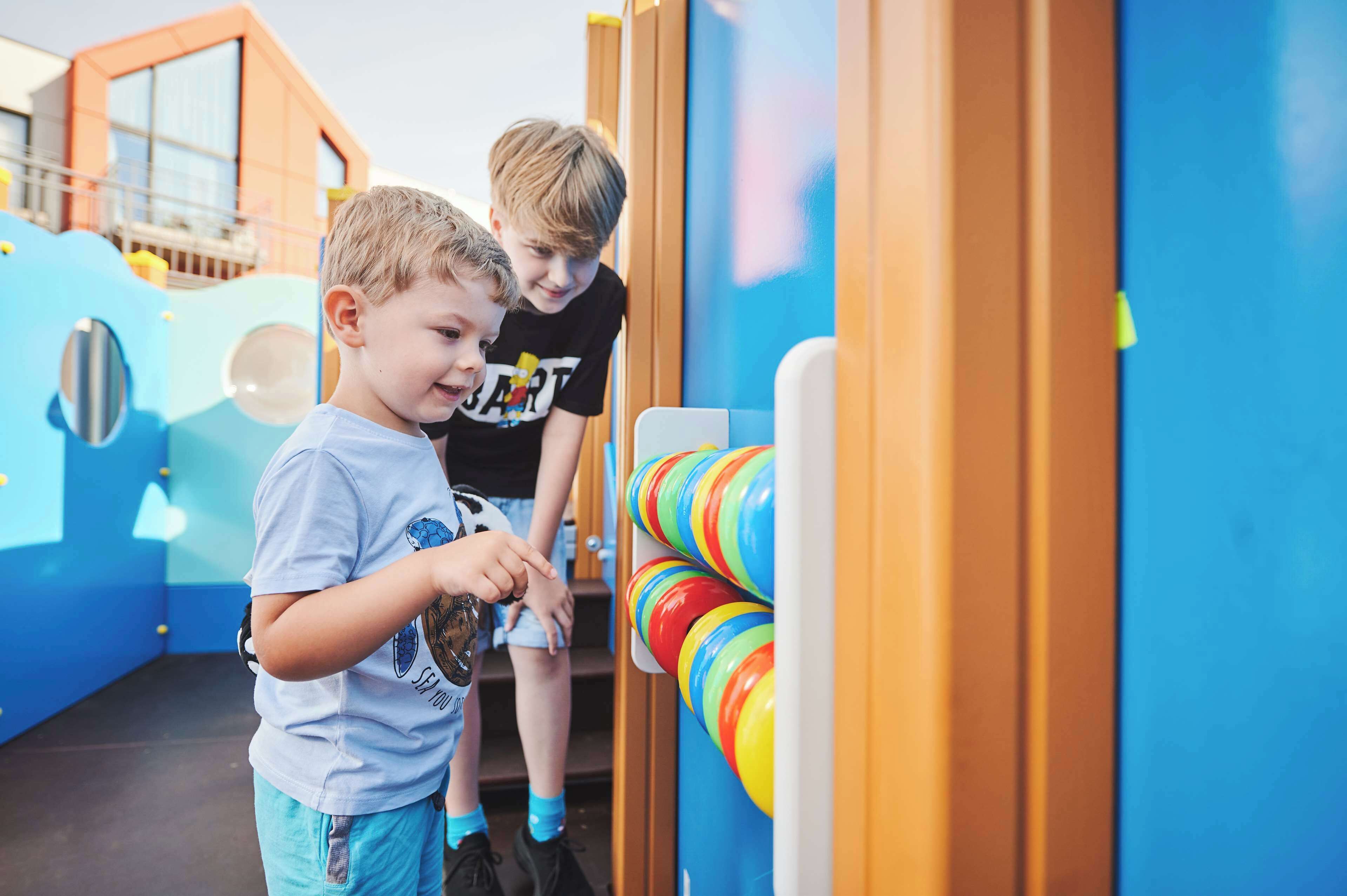 Dos niños jugando con una máquina de bolos arcade colorida.