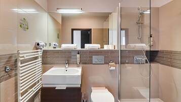 A modern bathroom with a bathtub, toilet, and shower.