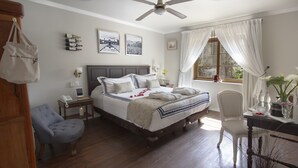A neatly arranged bedroom with a bed, bedside tables, a chair, a desk, and a window with curtains. - Carménère eco Hotel (Santiago)
