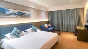 Habitación de hotel con cama, escritorio, silla, sofá y un cuadro en la pared.