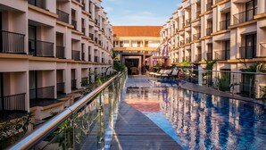 A modern hotel with a central pool, multiple balconies, and a well-maintained garden area. - Park Regis Kuta, Bali (Kuta)