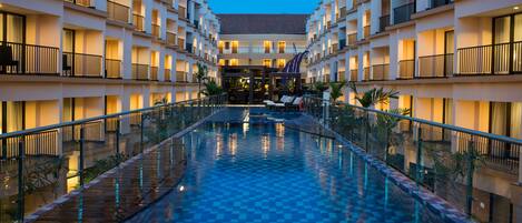 A hotel with a central swimming pool, multiple balconies, and a modern architectural design.