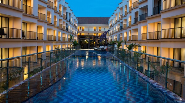 A hotel with a central swimming pool, multiple balconies, and a modern architectural design. - Park Regis Kuta, Bali (Kuta)