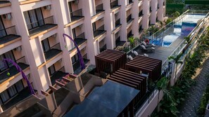 A multi-story hotel with balconies, a rooftop pool, and outdoor seating areas. - Park Regis Kuta, Bali (Kuta)