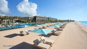 A beach resort with a pool area, sun loungers, and a hotel building. - Park Regis Kuta, Bali (Kuta)