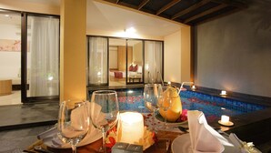 A dining table set with wine glasses, a candle, and a fruit arrangement. - Park Regis Kuta, Bali (Kuta)