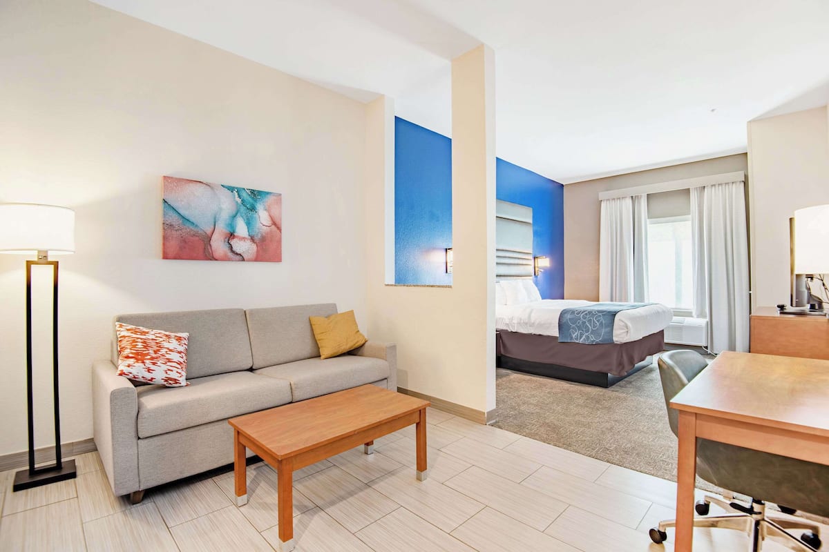 A hotel room with a sofa, a coffee table, a bed, and a desk.