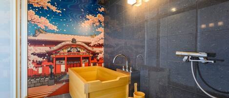 A modern bathroom with a large wooden bathtub, a shower, and a wall mural of cherry blossoms and a traditional building.