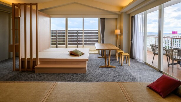 A hotel room with a large window, a wooden bed, a small table, and a balcony with chairs. - TATAMI NO YADO Chatan Mihama (Chatan)