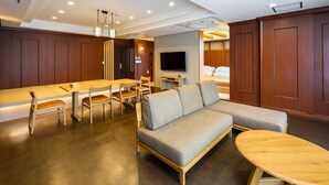 A modern hotel room with a dining area, a sofa, and a TV. - TATAMI NO YADO Chatan Mihama (Chatan)