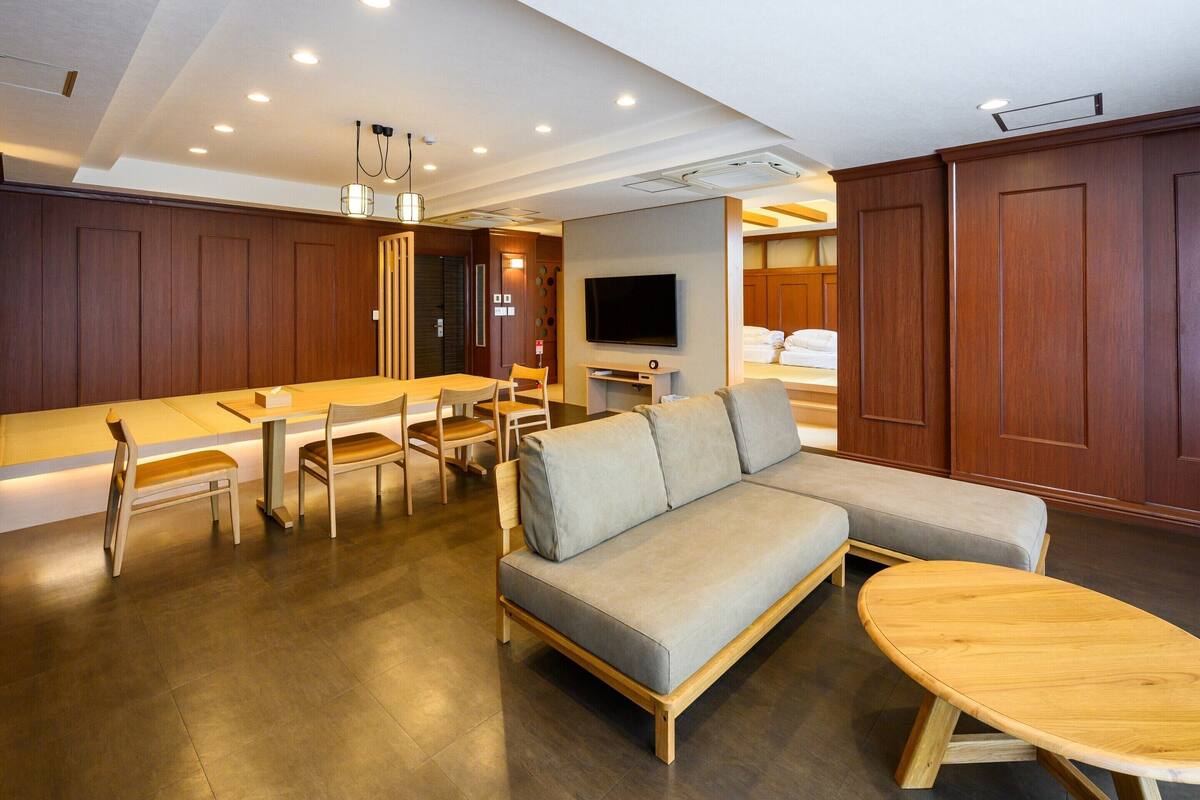 Ein modernes Hotelzimmer mit Essbereich, einer Couch und einem Fernseher.