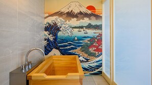 A bathroom with a wooden bathtub, a sink with a modern faucet, and a mural of Mount Fuji and the ocean. - TATAMI NO YADO Chatan Mihama (Chatan)