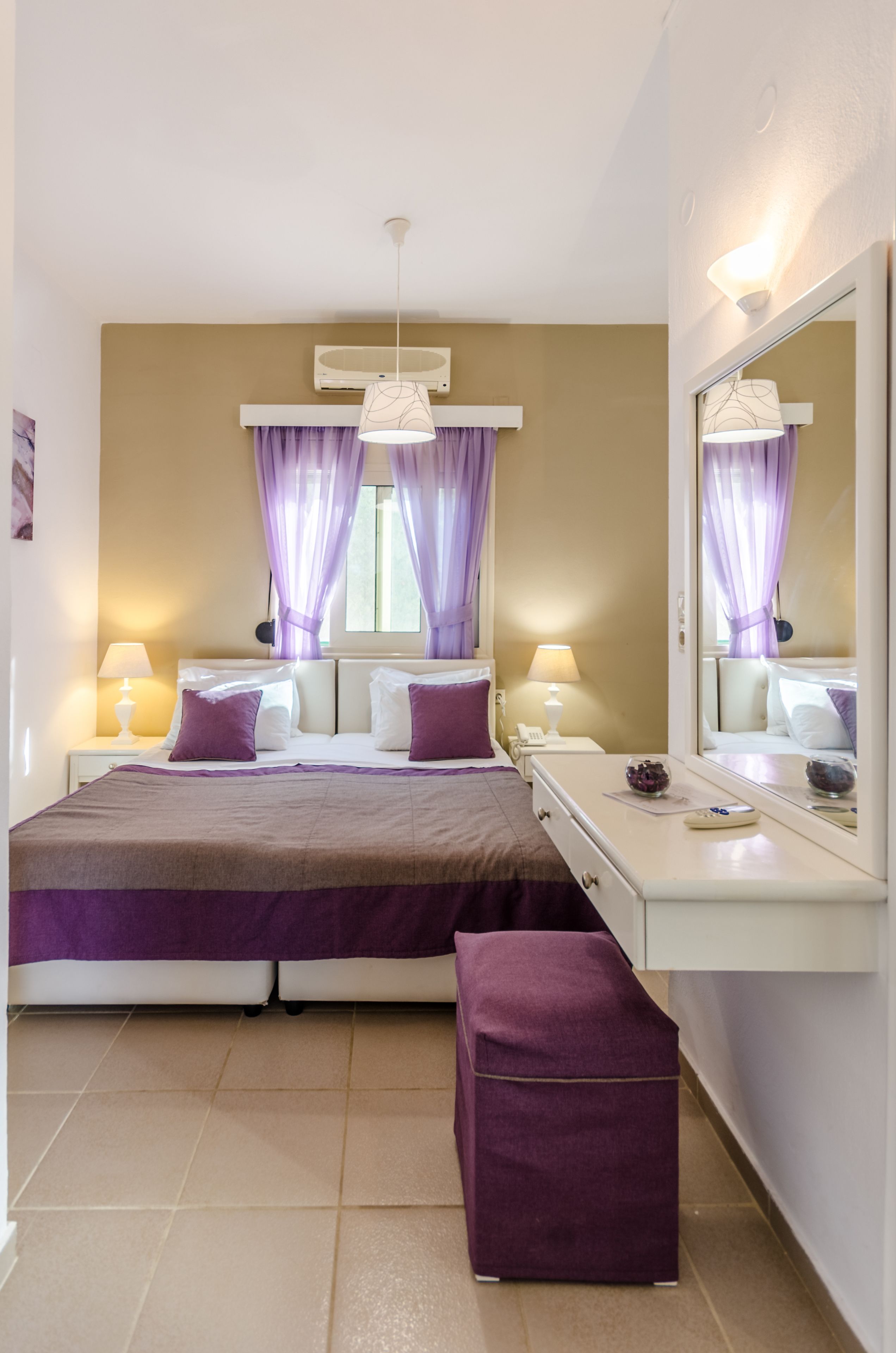 Un dormitorio con cama, mesitas de noche, un espejo y una ventana con cortinas.