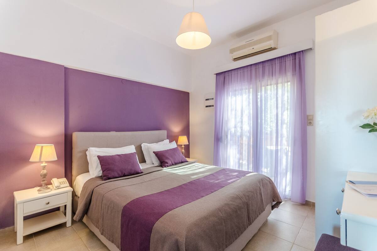 Une chambre à coucher comprenant un lit, une table de chevet, une lampe et un appareil de climatisation.
