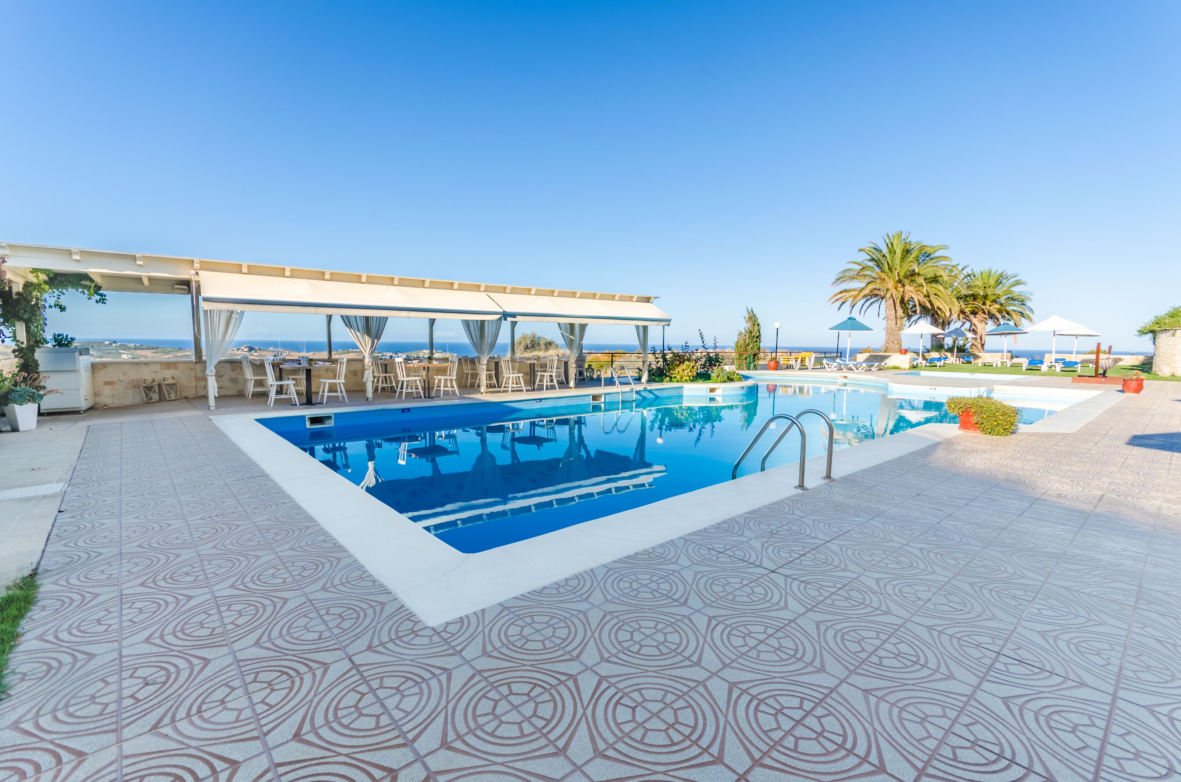 Zona de piscina amb vistes clares a l'oceà, cadiretes i ombrel·les.
