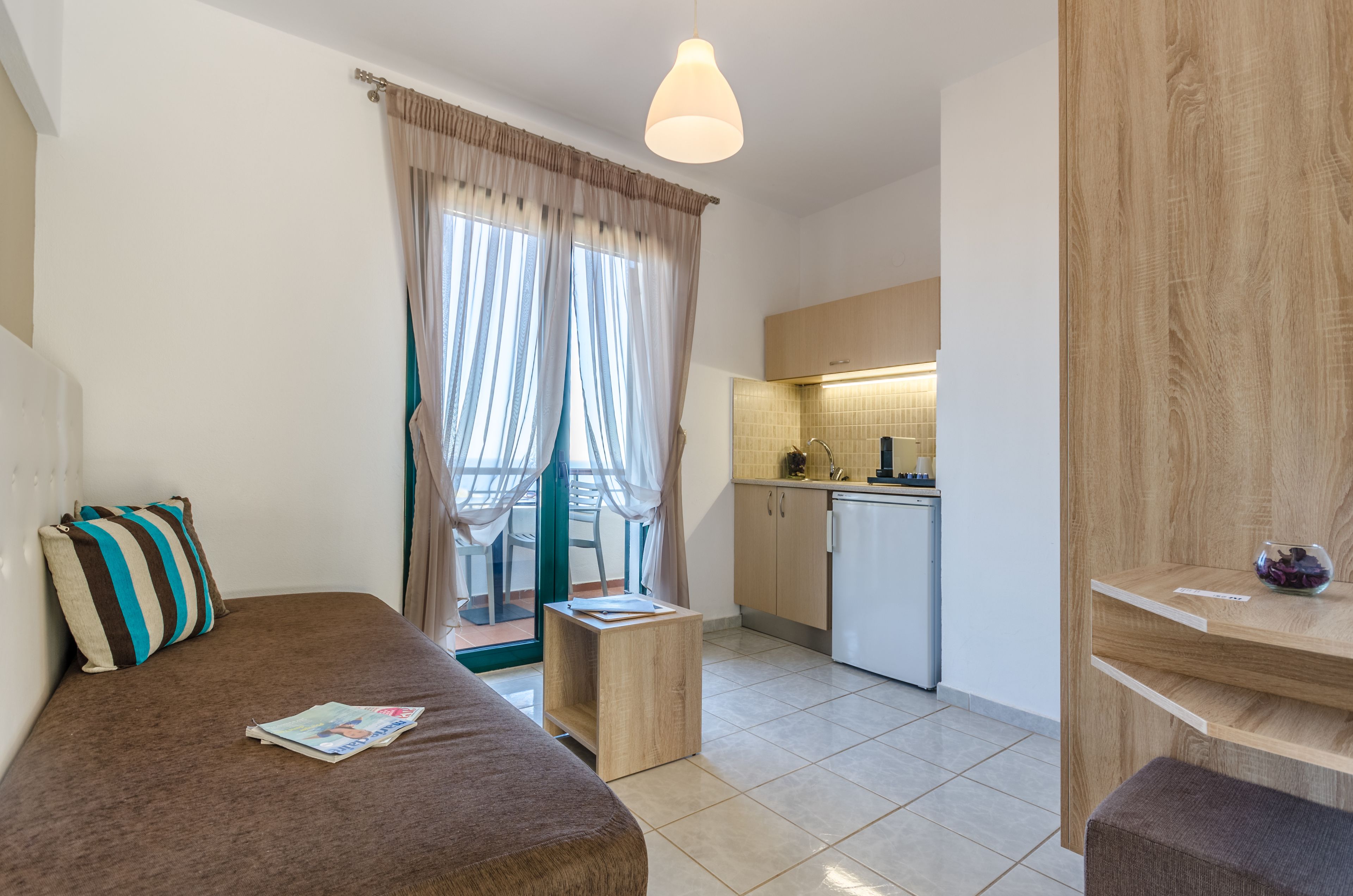 Una habitación moderna con sofá, una mesita de madera y una kitchenette.