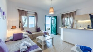 A modern hotel room with a bed, a sofa, a small table, a desk, and a kitchenette. - Pela Mare Hotel (Malevizi)