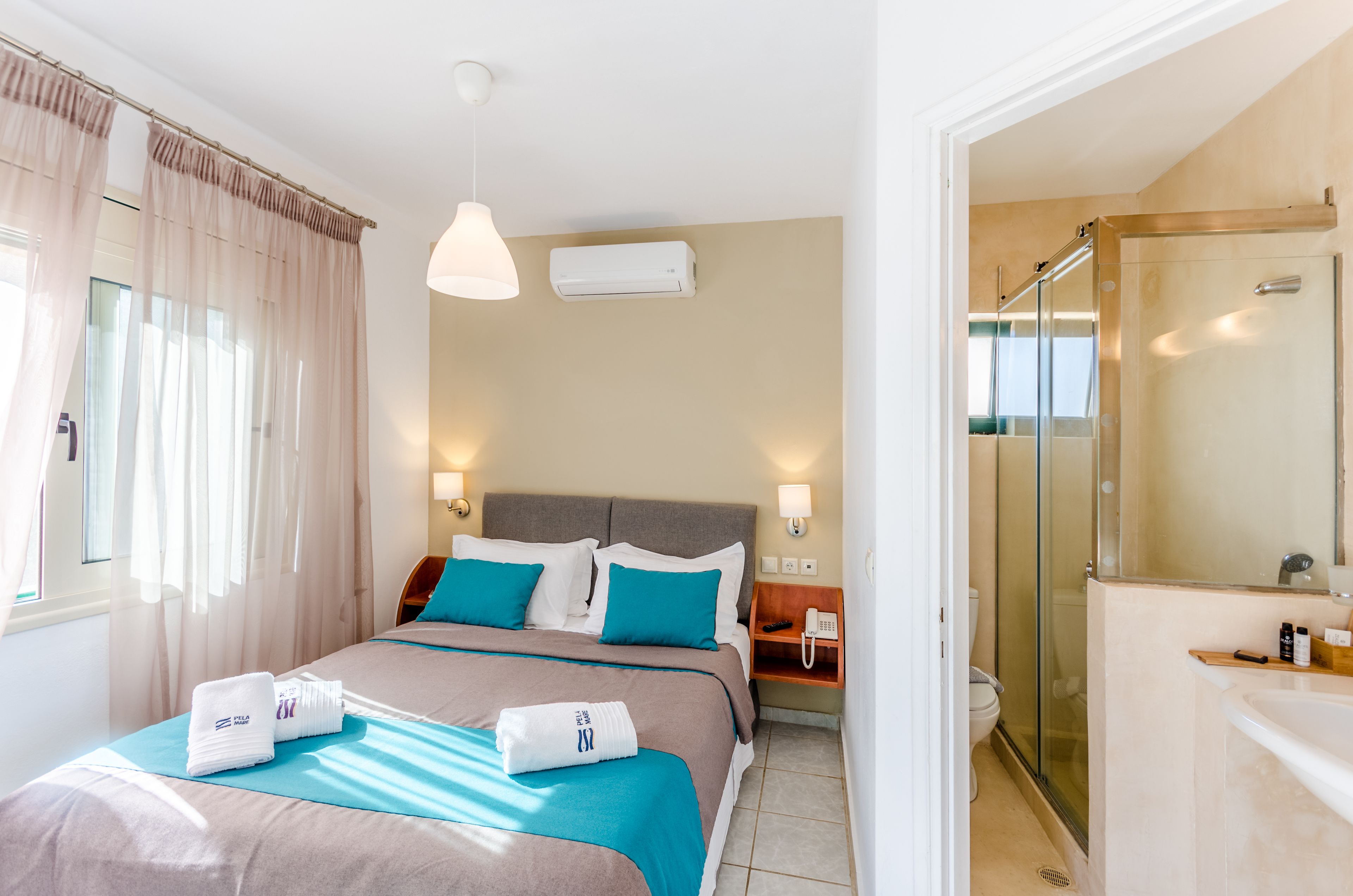 A hotel room with a bed, bedside table, and a shower area.