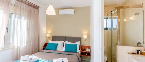 Habitación de hotel con cama, mesita de noche y zona de ducha.