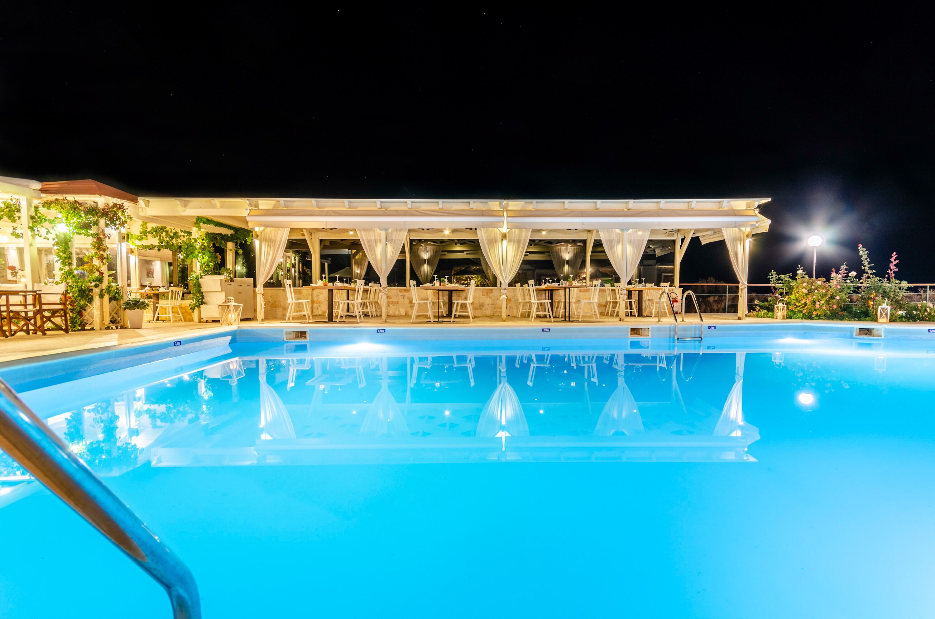 Un espace piscine aménagé pour la nuit, avec un coin salon abrité et une piscine à eau claire.