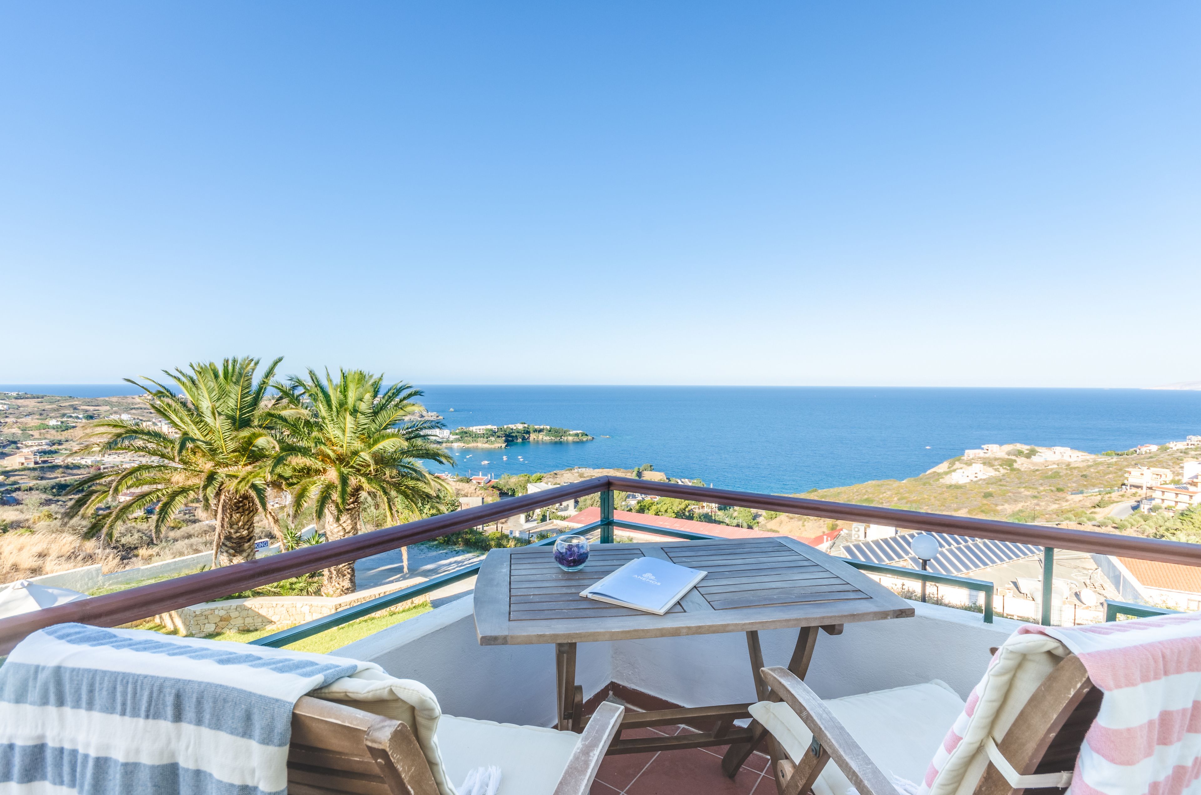 A balcony with a table, chairs, and a view of the sea.