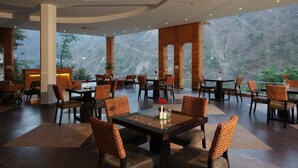 A spacious indoor dining area with high ceilings and large windows offering a mountain view. - Raga on the Ganges (Narendranagar)