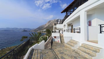 A white building with a stone staircase leading to a balcony overlooking the sea.