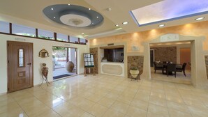 Un vestíbulo amplio con mostrador de recepción, zona de comedor y una gran puerta de madera.
