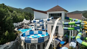 A water park with a large pool, multiple water slides, and a building with a red roof. - Mona Yongpyong Tower Condominium (Pyeongchang)