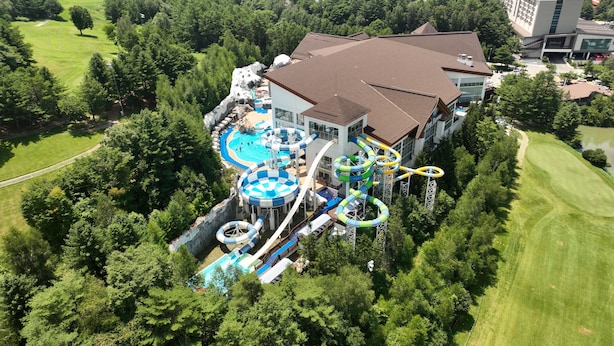 A large resort with a water park, including slides and pools, surrounded by lush greenery. - Mona Yongpyong Tower Condominium (Pyeongchang)