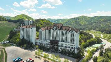 A multi-story hotel with a central courtyard, surrounded by lush greenery and hills.