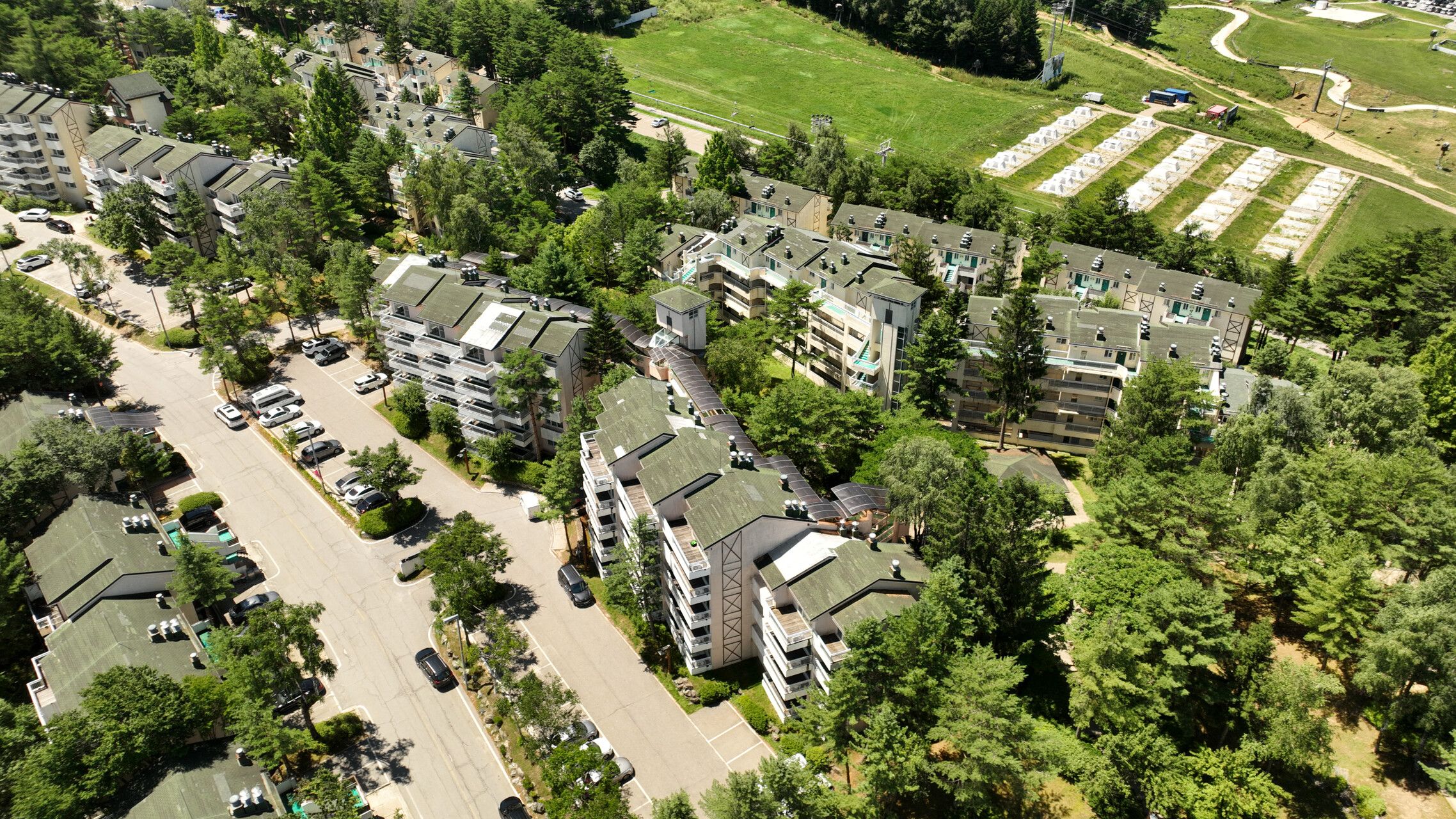 An aerial view of a residential area with multi-story buildings, parking lots, and green spaces.