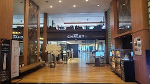 A modern interior with wooden flooring, a central seating area, and a visible restaurant named 'The Chalet'. - Mona Yongpyong Tower Condominium (Pyeongchang)