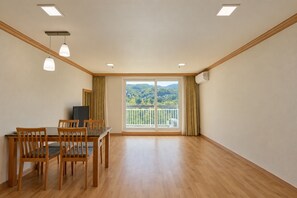 Habitación con una mesa de comedor, sillas, televisor y un balcón con vistas a zonas verdes.