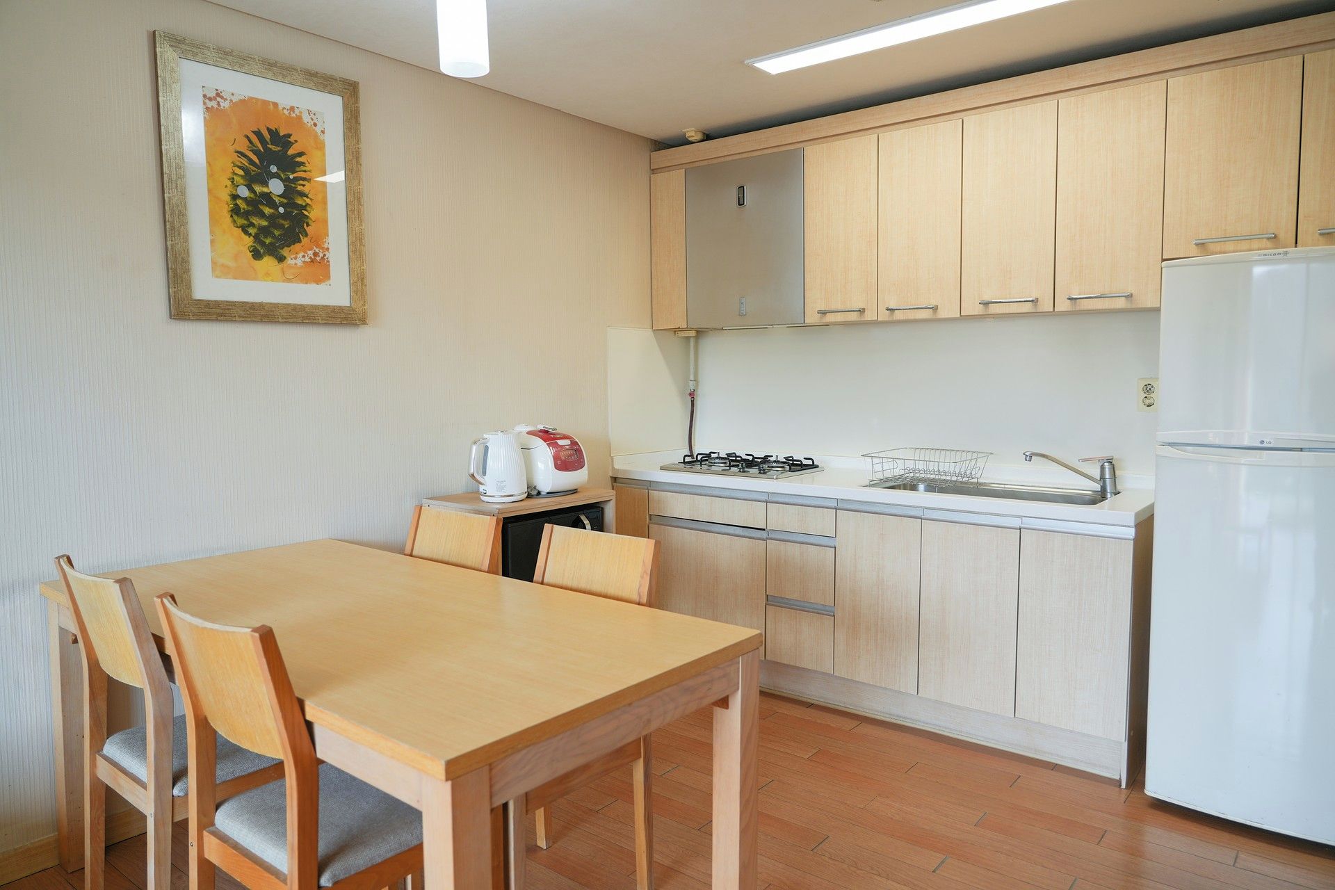 Une cuisine compacte comprenant une table et des chaises, un réfrigérateur et une cuisinière.