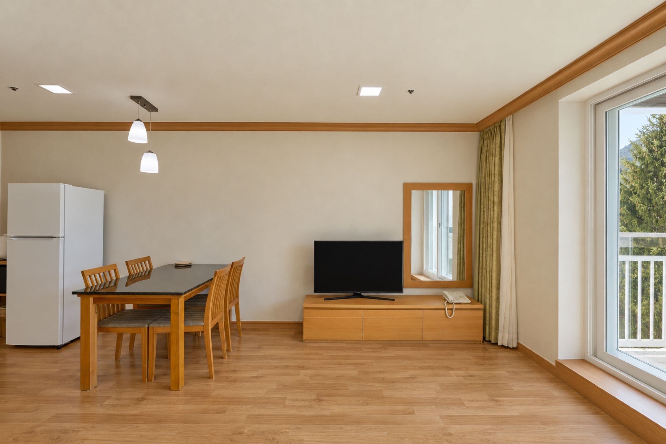 A modern living room with a dining area, a flat-screen TV, and a large window with curtains.